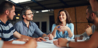 two men listen as a woman shares a story in a design meeting