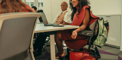 a black business woman in a motorized wheelchair laughs during a business meeting