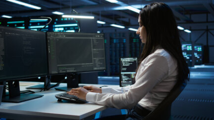 government UX designer works on efficiency in front of two screens