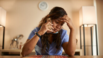 stressed filipina nurse taking phonecall at home